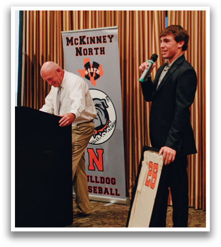 Two men stand on stage, one holding a microphone and the other holding a framed item. Contenido generado con IA