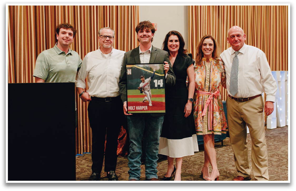 A group of people posing for a picture, one of them holding a framed baseball. Contenido generado con IA
