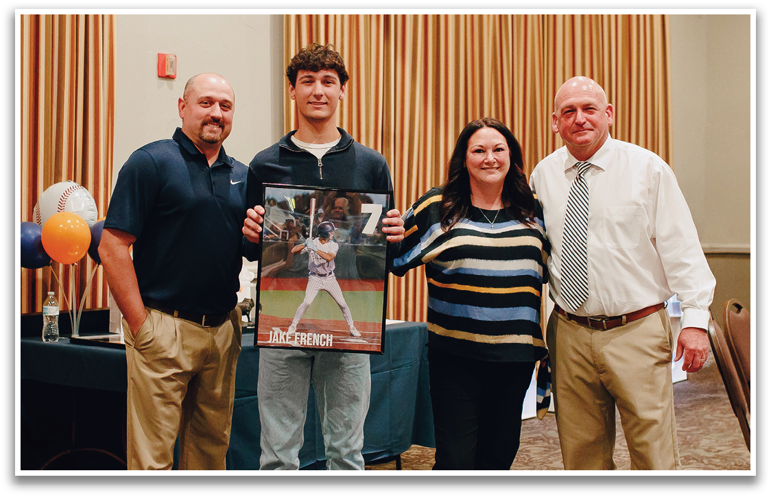 A group of people posing for a picture, one of the men is holding a framed photo of a baseball player. Contenido generado con IA