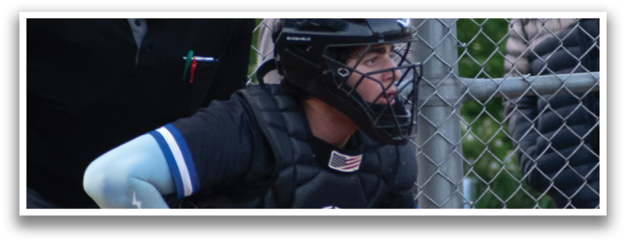 A baseball player is squatting on the ground wearing a black helmet. Description generated by AI