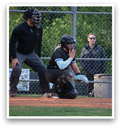 A baseball catcher wearing a black helmet and chest protector. Description generated by AI