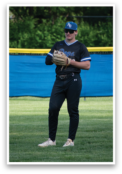 A baseball player wearing a black shirt and blue hat. Description generated by AI
