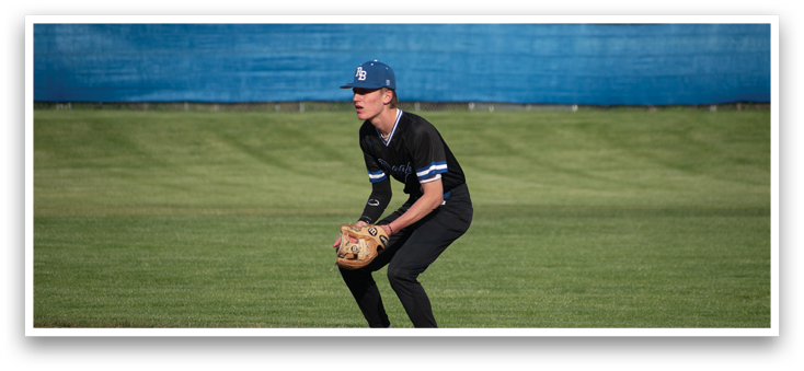 A baseball player in a black shirt and blue cap is holding a baseball mitt. Description generated by AI