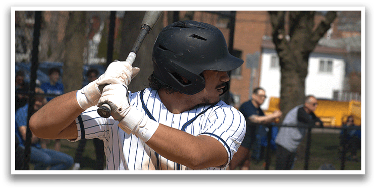 A baseball player in a white and blue uniform is swinging a bat. Description generated by AI
