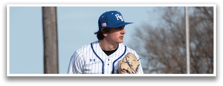 A baseball player in a blue hat and white uniform holding a baseball. Description generated by AI
