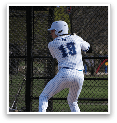A baseball player in a white and blue uniform is swinging a bat. Description generated by AI