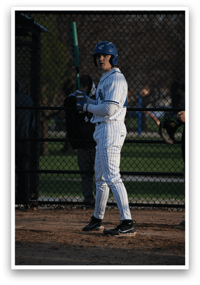 A baseball player in a white uniform holding a bat. Description generated by AI