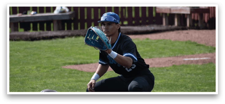 A baseball player in a black shirt and white shoes is kneeling on the ground. Description generated by AI