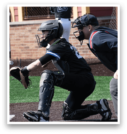 A baseball player in a black shirt and grey helmet is squatting down. Description generated by AI