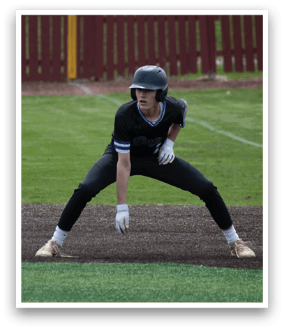 A baseball player in a black and blue uniform is crouching on the field. Description generated by AI