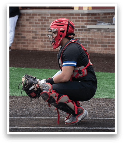 A baseball player in a red helmet and black uniform squatting down. Description generated by AI