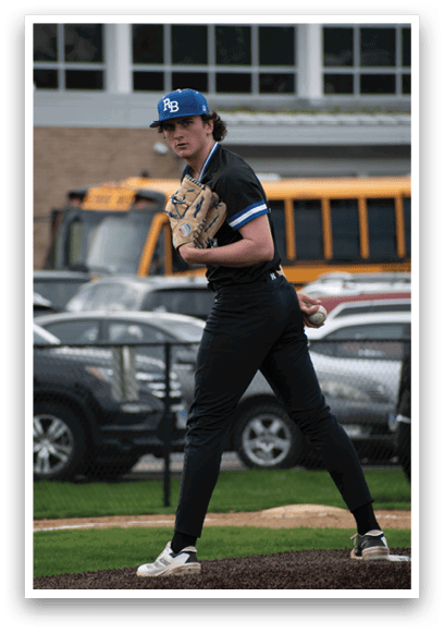 A baseball player in a black shirt and blue hat holding a baseball glove. Description generated by AI