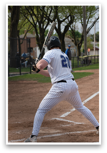 A baseball player in a white and blue uniform is swinging a bat. Description generated by AI