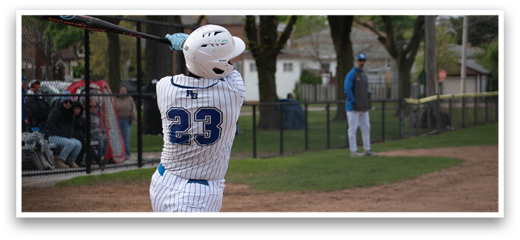 A baseball player in a white and blue uniform is swinging a bat. Description generated by AI