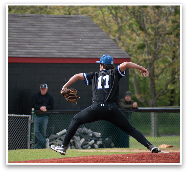 A baseball player in a black shirt and blue cap is pitching a ball. Description generated by AI