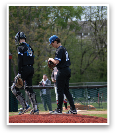 A baseball player wearing a blue and black uniform is standing on the pitcher's mound. Description generated by AI