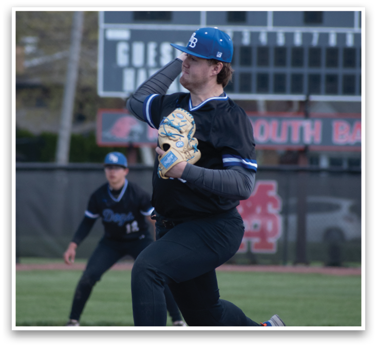 A baseball player in a black shirt and blue hat is throwing a ball. Description generated by AI