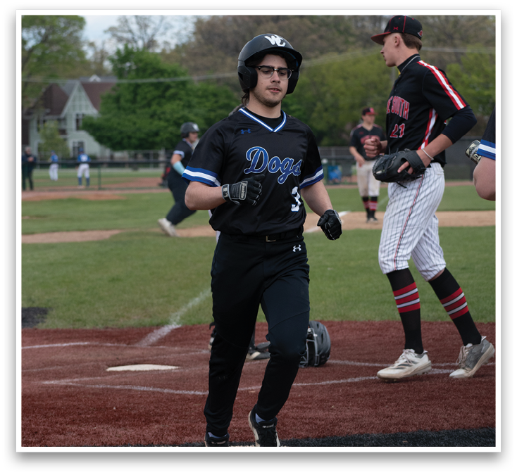 A baseball player wearing a black shirt and white pants with the word “Dukes" on the front. Description generated by AI