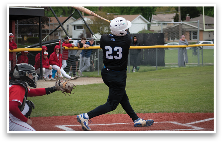 A baseball player in a black shirt and blue shorts is swinging a bat. Description generated by AI