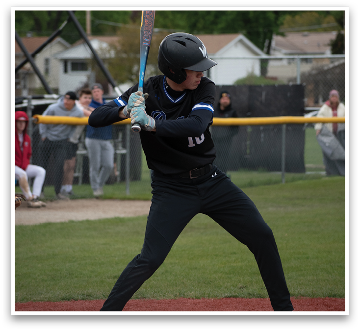 A baseball player in a black shirt and blue helmet is swinging a bat. Description generated by AI