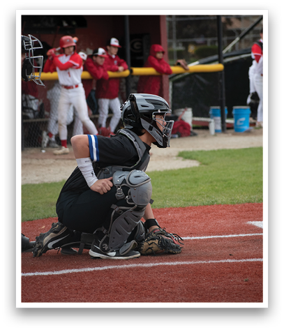 A baseball catcher squatting on the field. Description generated by AI