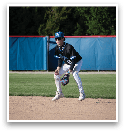 A baseball player in a black and blue uniform is standing on a field. Description generated by AI