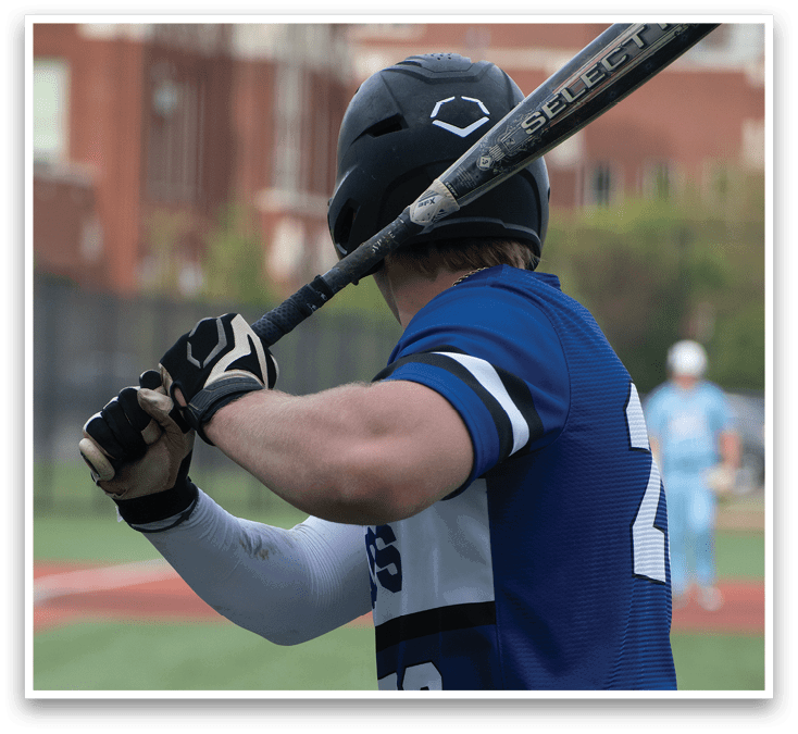 A baseball player in a blue and white uniform is holding a bat. Description generated by AI