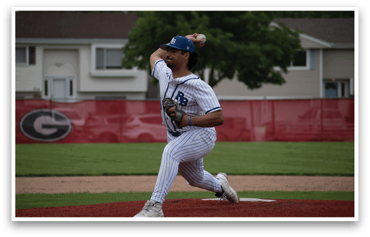 A baseball player in a white and blue uniform is pitching a ball. Description generated by AI