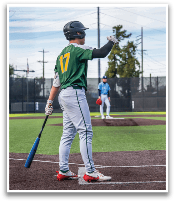 A baseball player in a green and yellow jersey is holding a bat, preparing to swing. Another player is standing nearby, wearing a blue shirt. The scene takes place on a baseball field. AI generated content