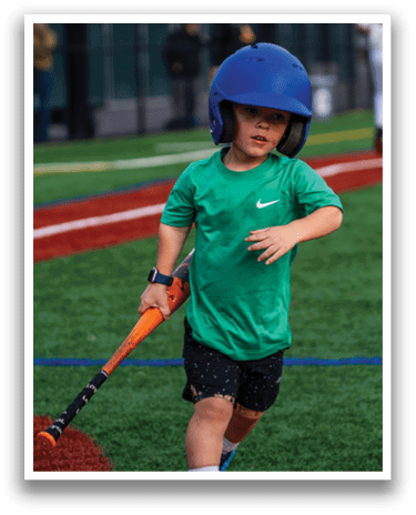 A young boy wearing a blue helmet and green shirt is holding a baseball bat, ready to swing. AI generated content