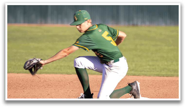 A baseball player wearing a green and yellow uniform is kneeling on the ground with his glove on. Description generated by AI