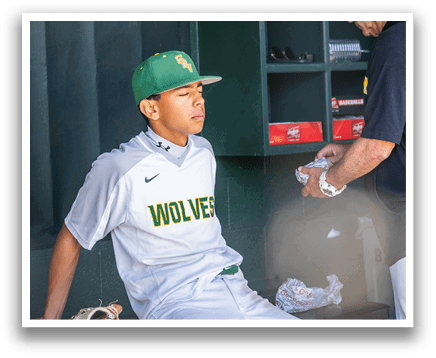 A baseball player wearing a green and yellow hat sits on a bench. Description generated by AI
