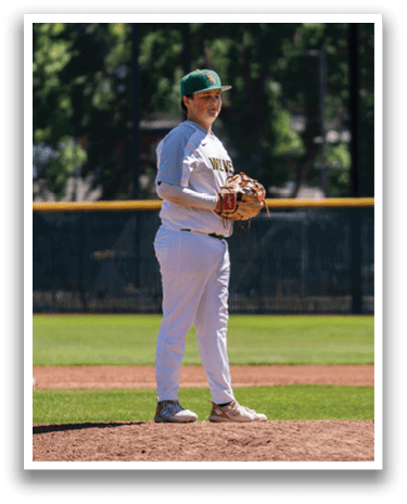 A baseball player in a white uniform stands on a mound. Description generated by AI