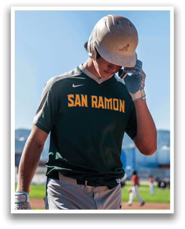A baseball player wearing a green and yellow shirt and grey pants is holding a bat and talking on his cell phone. AI generated content