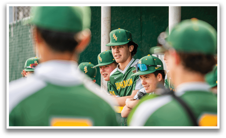 A group of young men wearing green baseball caps and jerseys are sitting on a bench. AI generated content