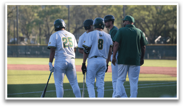 Three baseball players wearing green and white uniforms are standing on a field. They are holding baseball bats and talking to each other. AI generated content