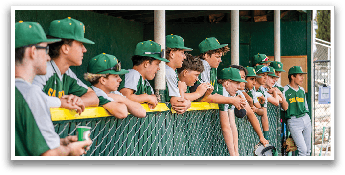 Baseball players in a dugout, some sitting and some standing, wearing green and yellow uniforms. AI generated content