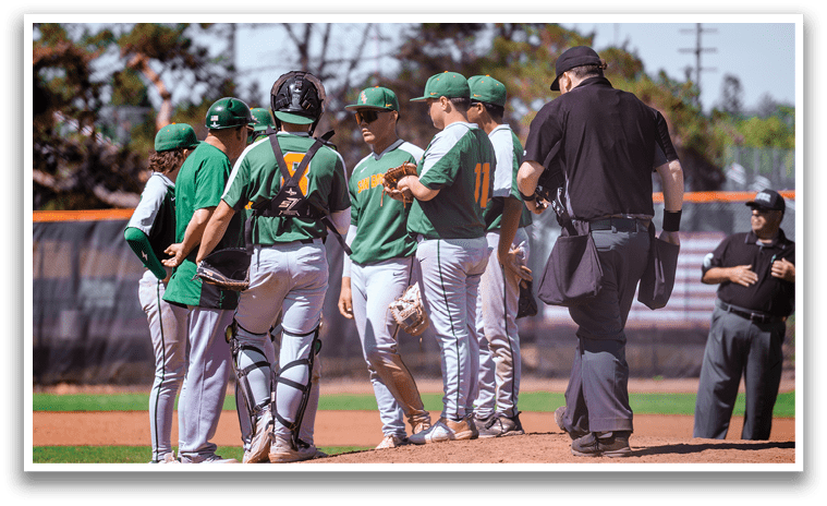 A group of baseball players wearing green and white uniforms are standing on the field. They are engaged in conversation with an umpire, who is also wearing a green shirt. The players are holding baseball bats, and one of them is holding a baseball glove. AI generated content