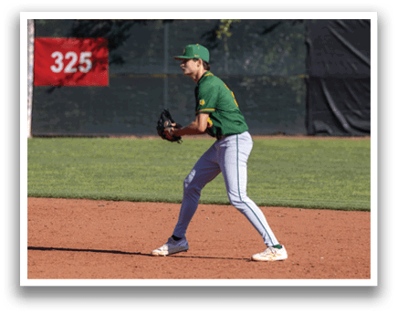 A baseball player wearing a green and yellow uniform is standing on a baseball field. Description generated by AI