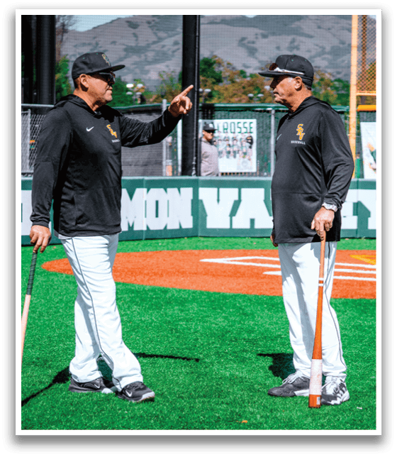 Two men standing on a baseball field. Description generated by AI