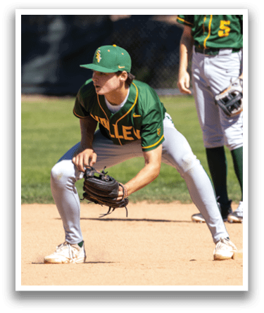A boy in a green and yellow baseball uniform is kneeling on the ground with a baseball glove on. Description generated by AI
