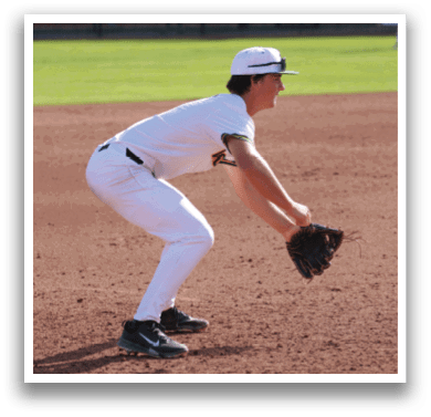 A baseball player in a white uniform is crouching on the field. Description generated by AI