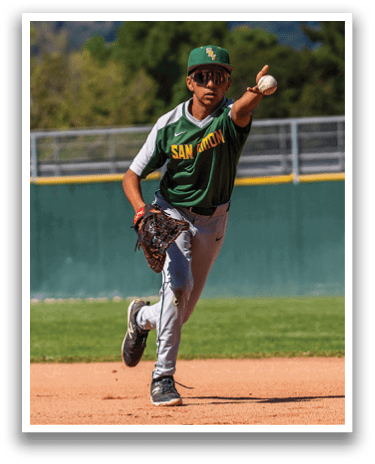 A baseball player in a green and white jersey is running to catch a ball. Description generated by AI