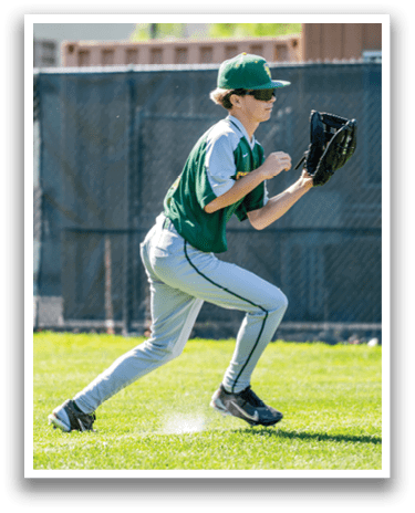 A boy in a green and white baseball uniform is running on a grass field. Description generated by AI