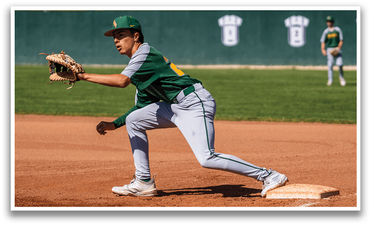 A baseball player wearing a green and yellow uniform is running towards a base. Description generated by AI