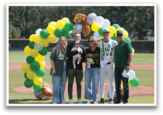 A group of people standing in front of a baseball field. Description generated by AI