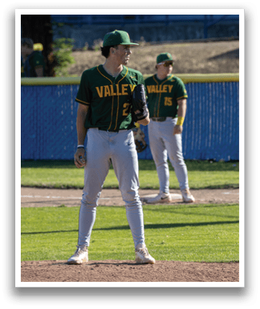 A baseball player wearing a green and yellow jersey stands on the pitcher's mound. Description generated by AI