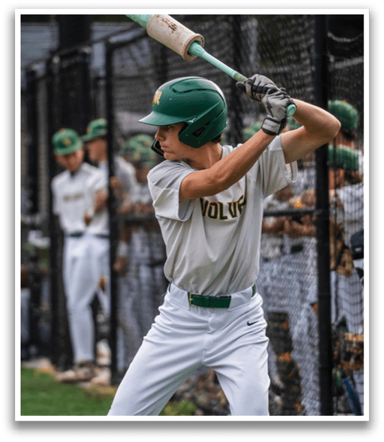A baseball player in a green helmet and white uniform is swinging a bat. Description generated by AI