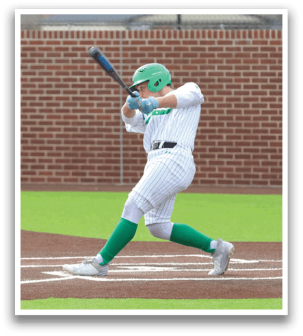 A baseball player in a green shirt and white pants is swinging a bat at a ball. Contenido generado con IA