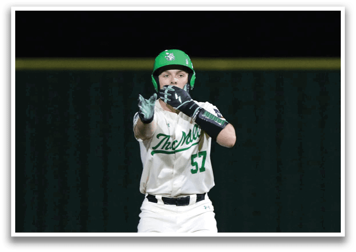 A baseball player wearing a green helmet and white uniform stands on the field. Contenido generado con IA